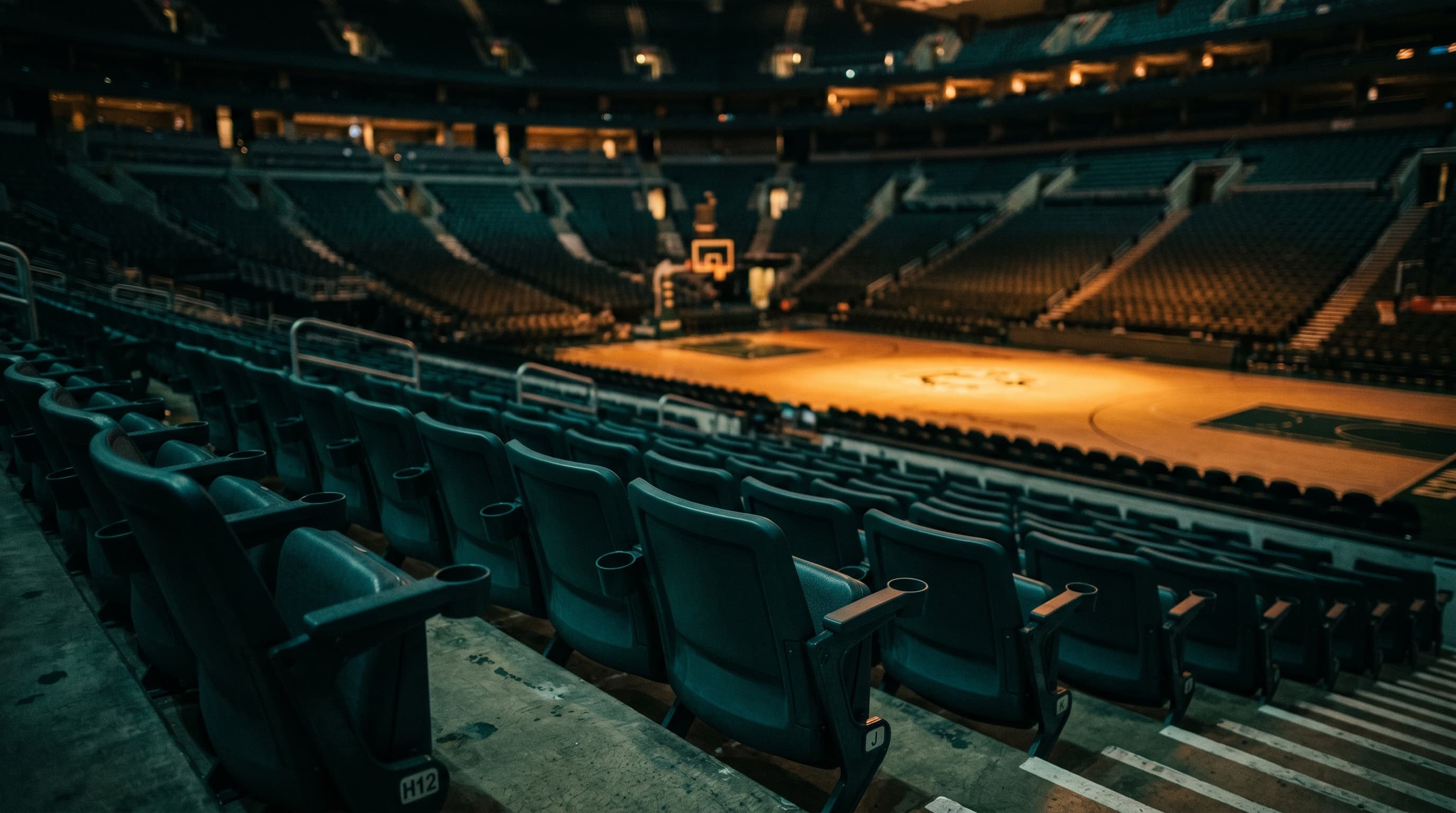 Tribüne einer Indoor-Sport-Arena mit Sitzreihen im Vordergrund, Court in weicher Unschärfe im Hintergrund